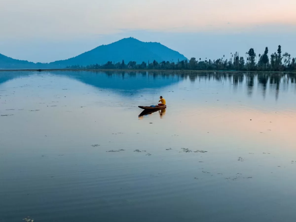 Dal Lake Srinagar Kashmir golden hour wooden shikara Zabarwan mountains, yellow jacket fisherman calm reflective waters sunset peaks, perfect Jammu Kashmir Dal Lake solitude package.