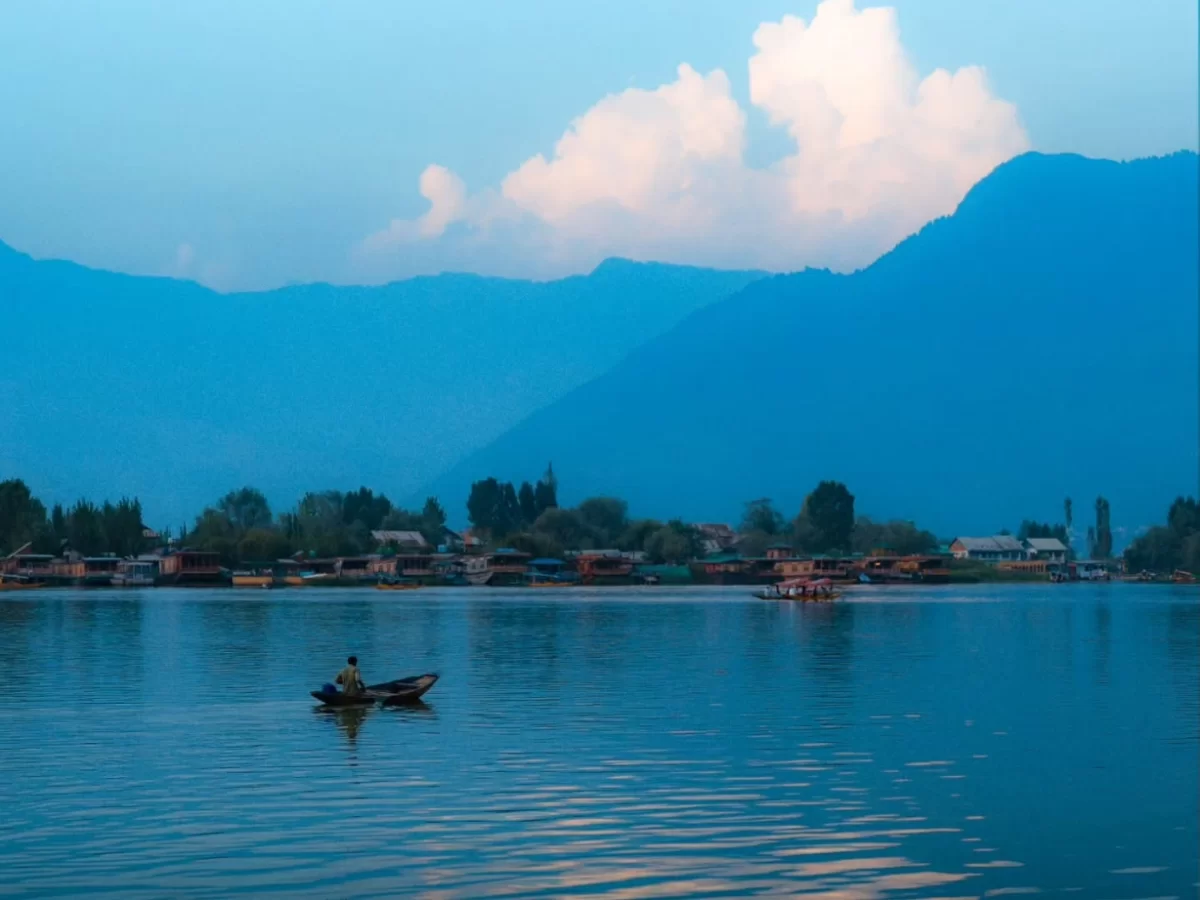 Dal Lake Srinagar Kashmir blue hour fisherman wooden shikara Zabarwan mountains, houseboats clouds sunset reflections calm waters, perfect Jammu Kashmir Dal Lake twilight serenity package.