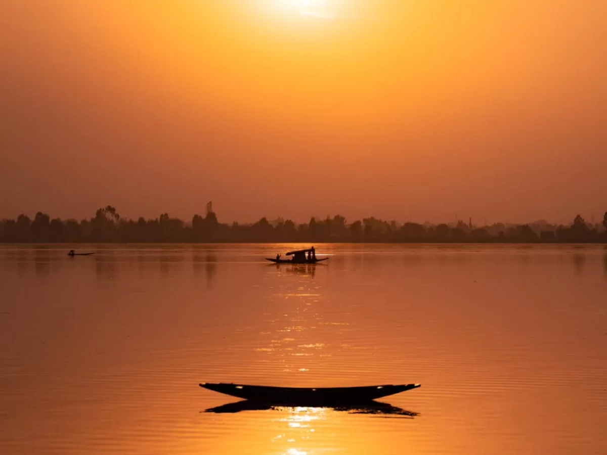 Dal Lake Srinagar Kashmir dramatic orange sunset silhouette shikara fishermen, houseboats hazy mountains golden reflections calm waters, perfect Jammu Kashmir Dal Lake sunset magic package.