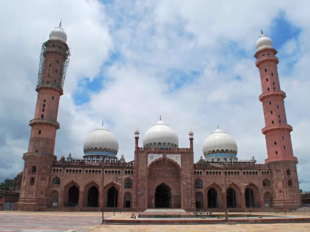Taj-ul-Masajid at Bhopal during partly cloudy day, featuring pink minarets white domes courtyard, perfect cultural Madhya Pradesh tour package.