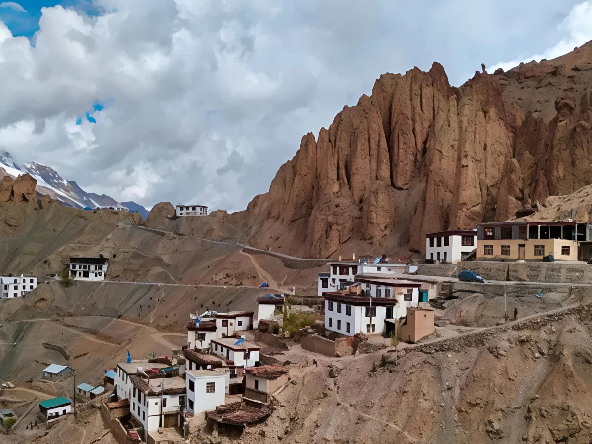 Dhankar Monastery village near Kaza Spiti Valley Himachal Pradesh during partly cloudy skies, featuring white monasteries terraced rocky cliffs red pinnacles distant snow peaks, perfect cultural experience Himachal tour package.