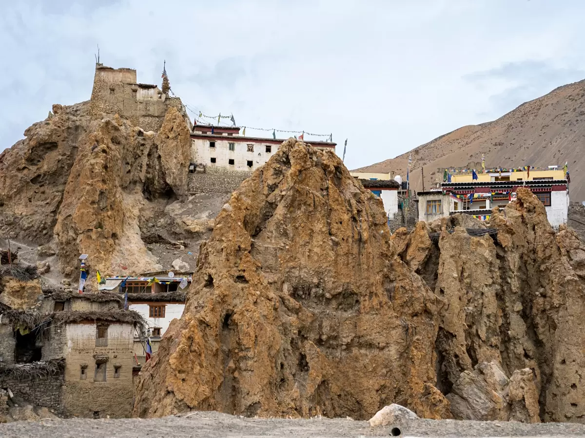 Dhankar Monastery near Kaza Spiti during cloudy skies, featuring white castle-like monastery rocky cliffs prayer flags brown hills, perfect cultural experience Himachal tour package.