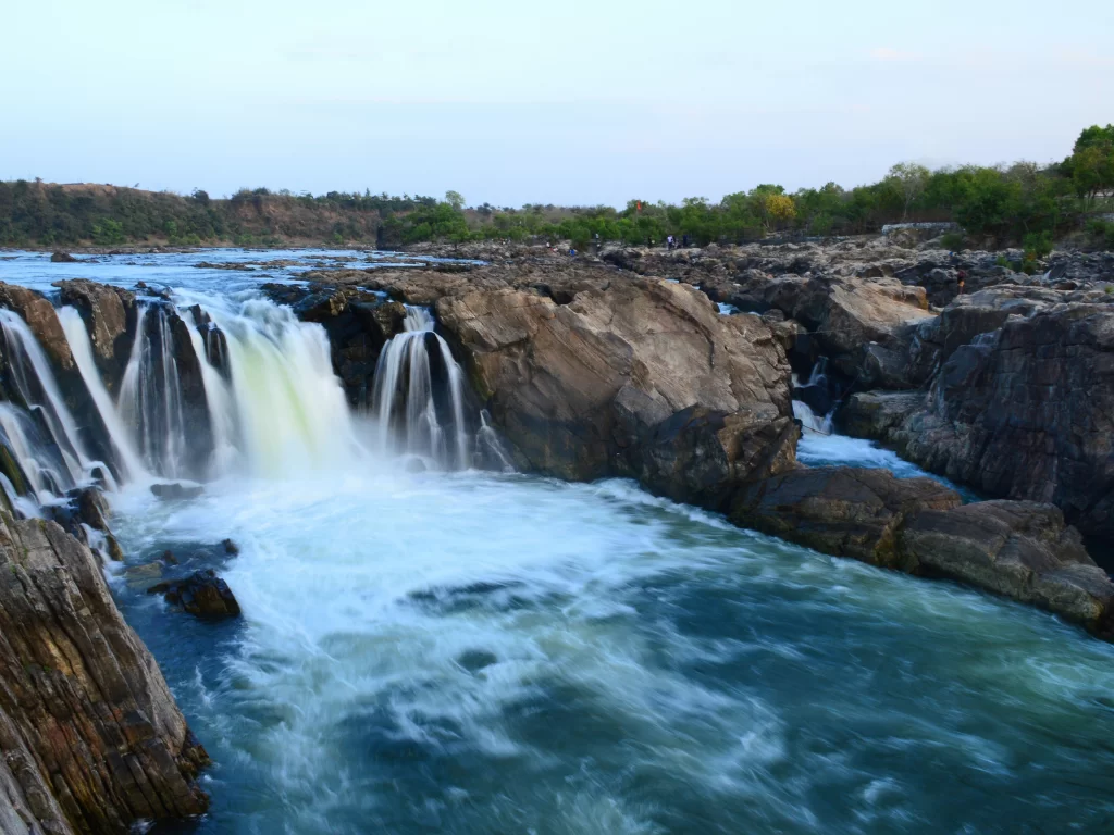 Dhuandhar Falls at Bhedaghat Jabalpur during sunset twilight, featuring Narmada River cascades through marble gorges and lush banks, perfect adventure experience in Madhya Pradesh tour package.