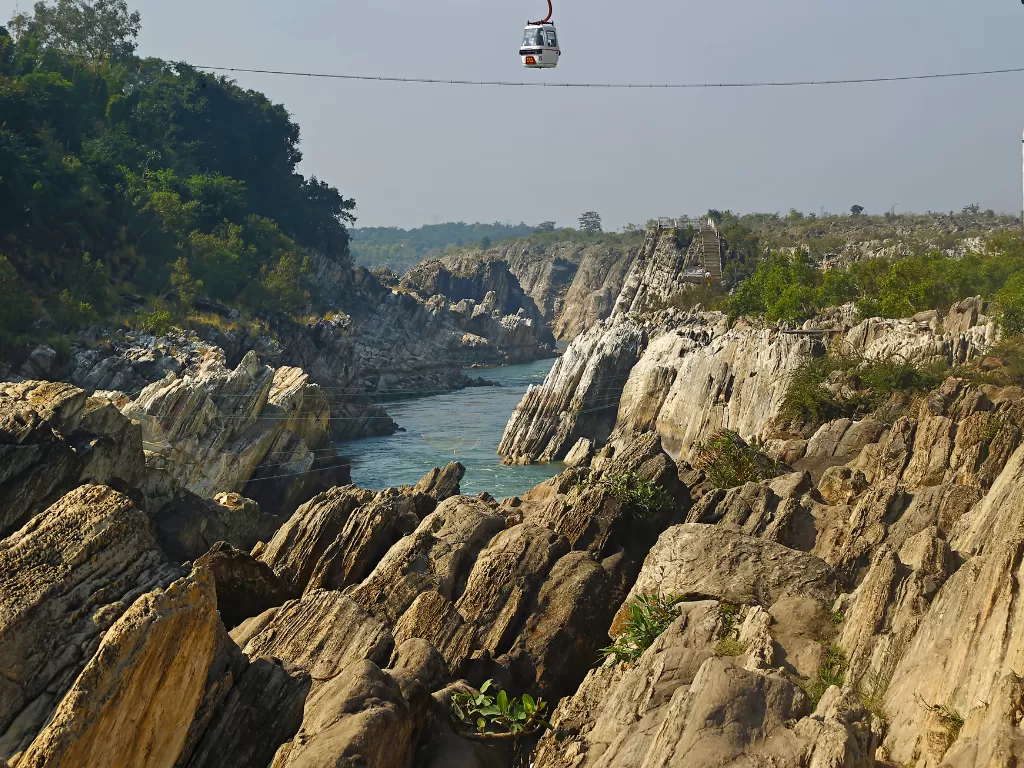 Cable car ride at Dhuandhar Falls Bhedaghat during clear afternoon, featuring Narmada River marble gorges and lush hills, perfect adventure experience in Jabalpur tour package.