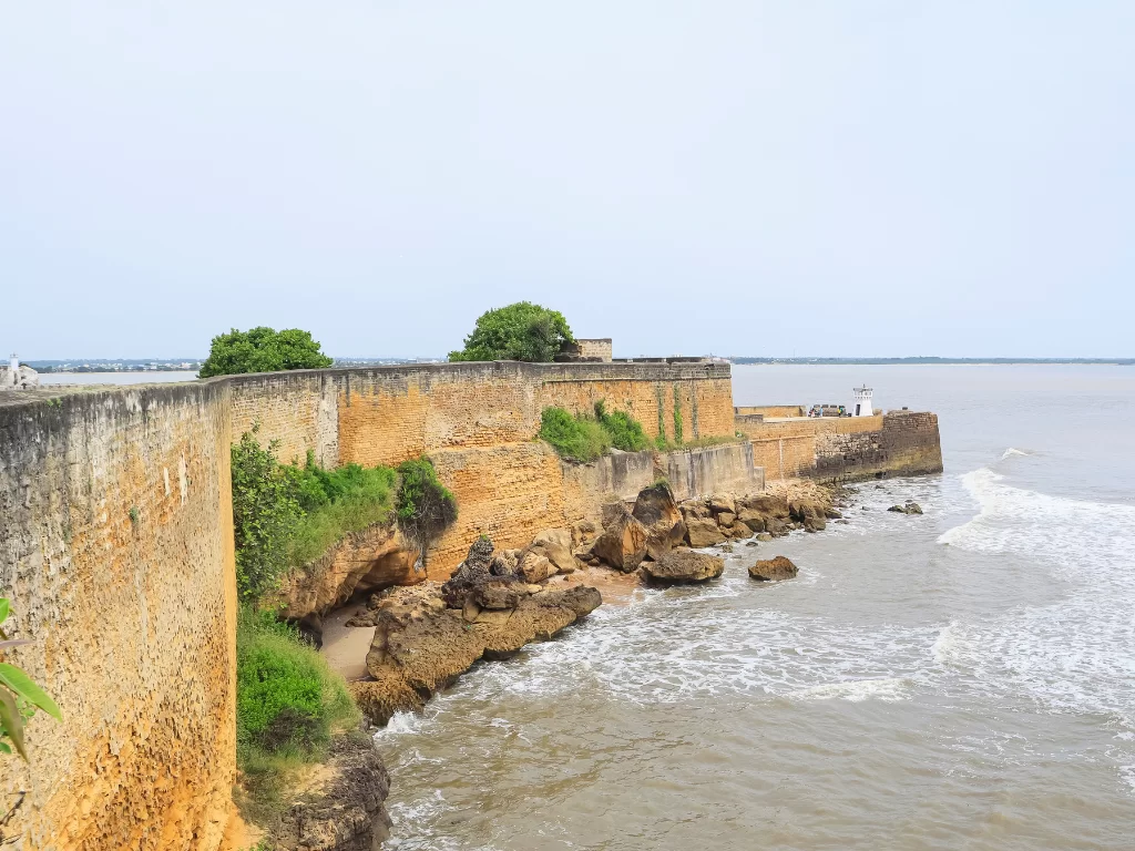 Fort walls at Diu Fort during daylight, featuring ocean waves and lighthouse, perfect adventure Diu tour package.