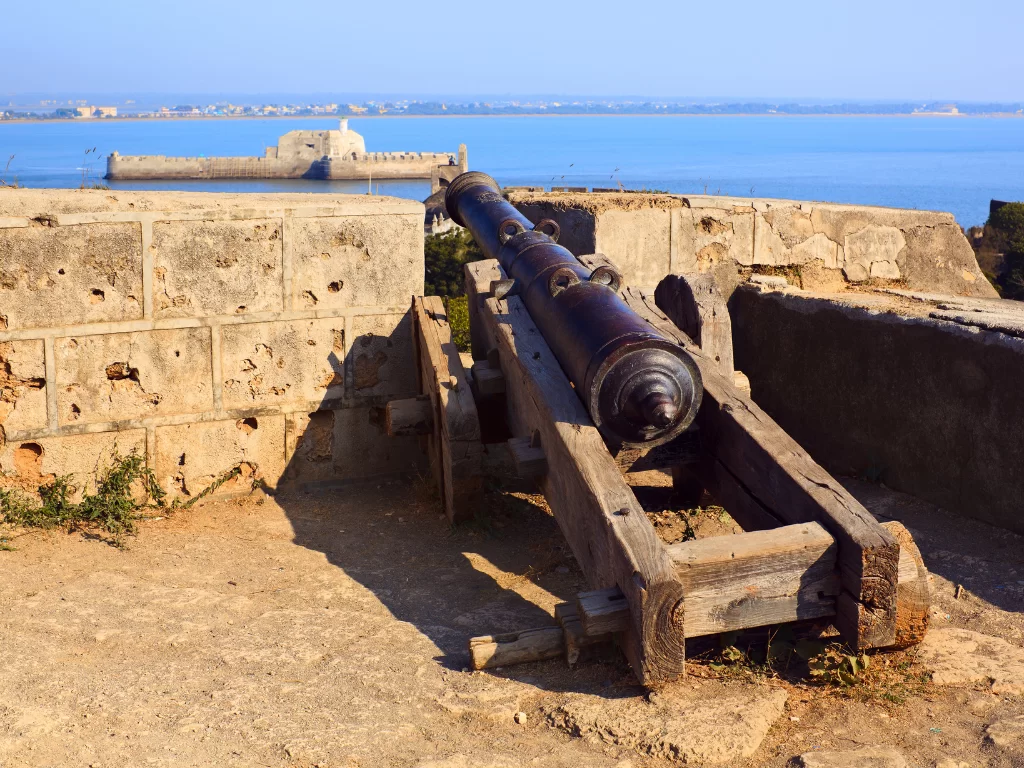 Cannon at Diu Fort during clear daylight, featuring ocean views and bastions, perfect adventure Diu tour package.
