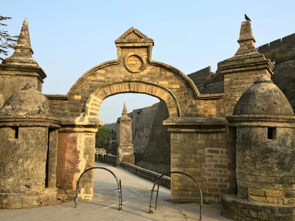 Grand entrance at Diu Fort during daylight, featuring ornate arches and bastions, perfect adventure Diu tour package.