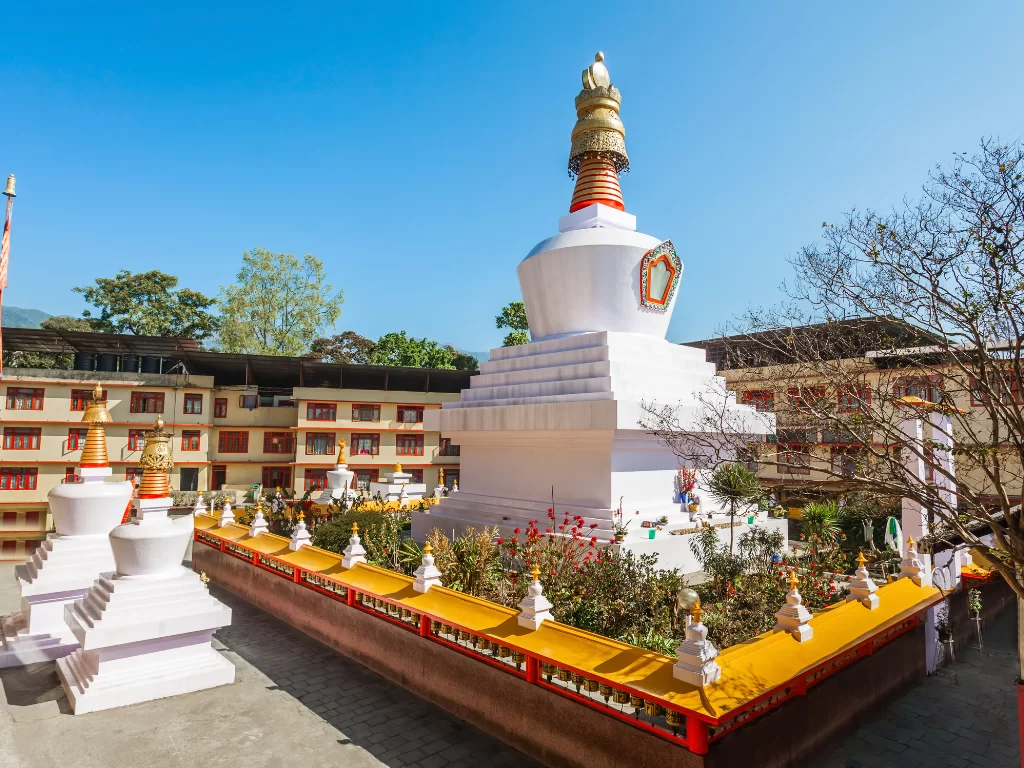 Do Drul Chorten stupa in Gangtok during sunny daytime, featuring prayer walls, gardens and blue sky, perfect spiritual Sikkim tour package