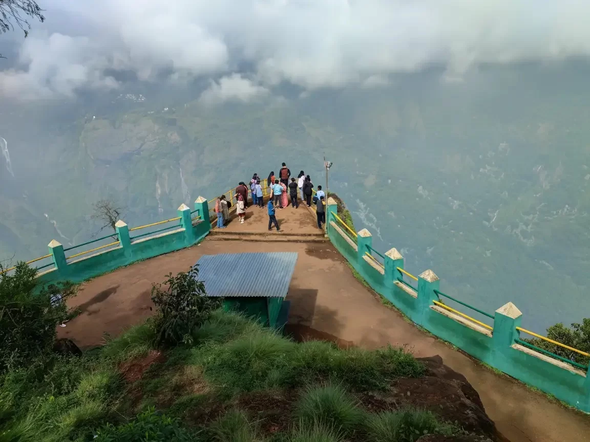 Dolphin's Nose viewpoint in Kodaikanal featuring a flat projecting rock over a deep precipice with misty green mountains.