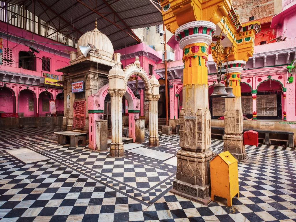 Shri Dwarkadhish Temple Kankroli Rajsamand Rajasthan pink haveli-style courtyard with ornate yellow pillars, carved arches, checkered black-white marble floor under metal roof, perfect Vaishnava heritage India tour package