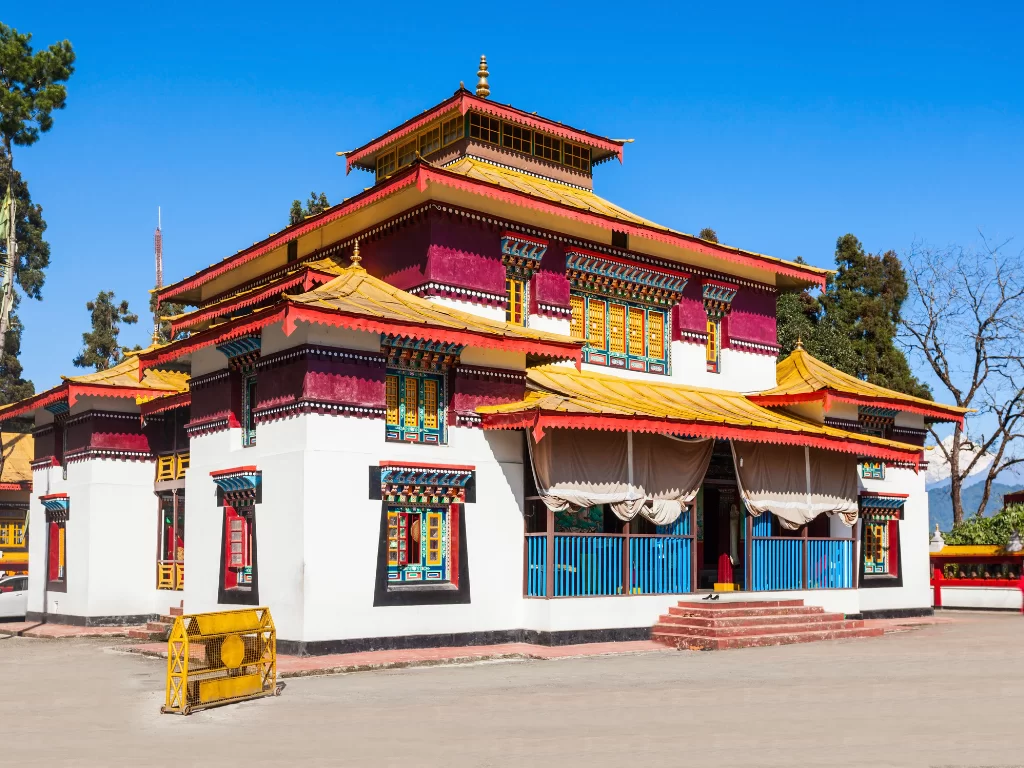 Colorful facade of Enchey Monastery in Gangtok during sunny daytime, featuring vibrant Tibetan windows and clear blue sky, perfect spiritual Sikkim tour package