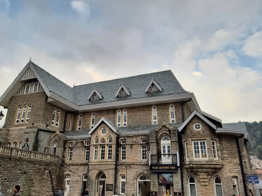 Gaiety Heritage Cultural Complex Shimla Gothic Revival stone building with arched windows gables cloudy sky hill backdrop, perfect heritage cultural landmark, Himachal Pradesh tour packages.