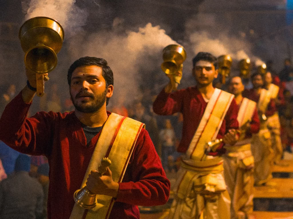 Priests performing Ganga Aarti at Varanasi during evening, featuring lamps smoke crowds, perfect spiritual Uttar Pradesh tour package.