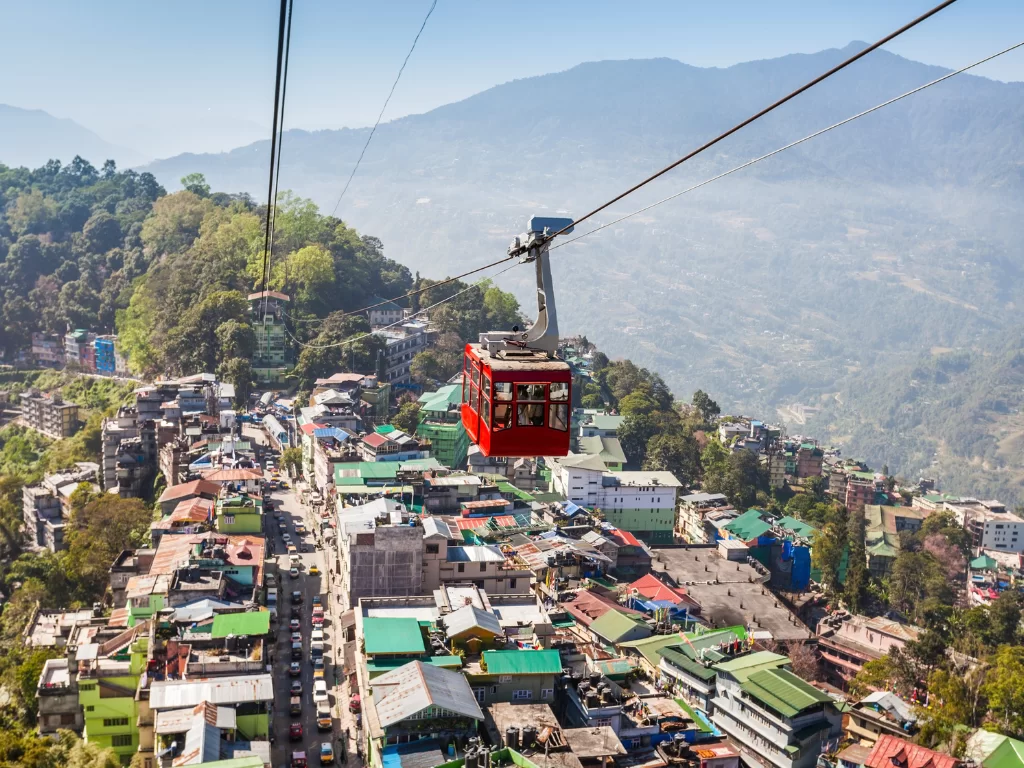 Gangtok ropeway Sikkim during clear skies, featuring red cable car cityscape valley views, perfect family sightseeing experience Sikkim tour package.