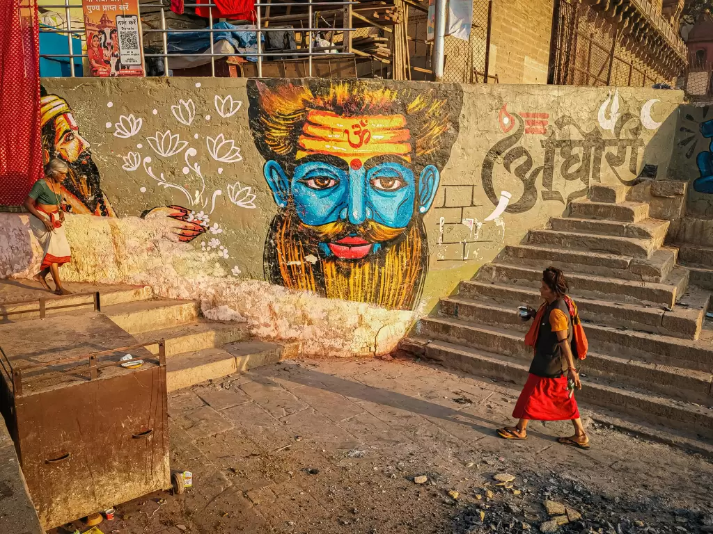 Vibrant Shiva mural at Varanasi ghat during sunset, featuring blue face lotuses stairs, perfect cultural Uttar Pradesh tour package.