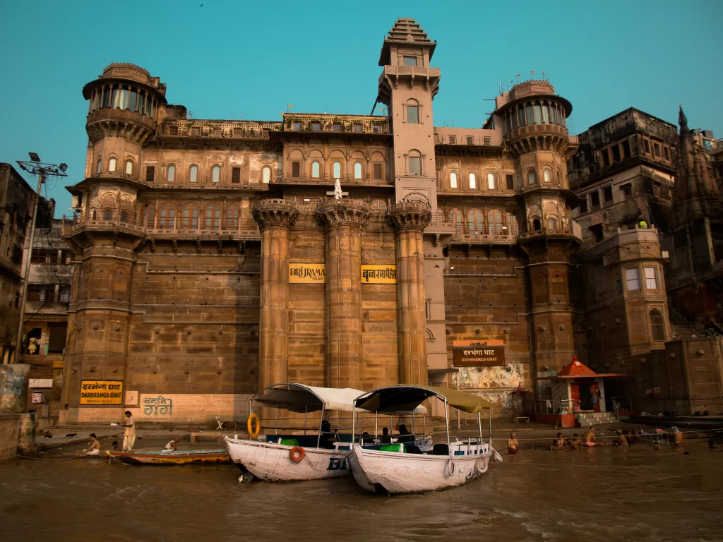 Darbhanga Ghat palace at Varanasi during golden hour, featuring boats towers river views, perfect cultural Uttar Pradesh tour package.