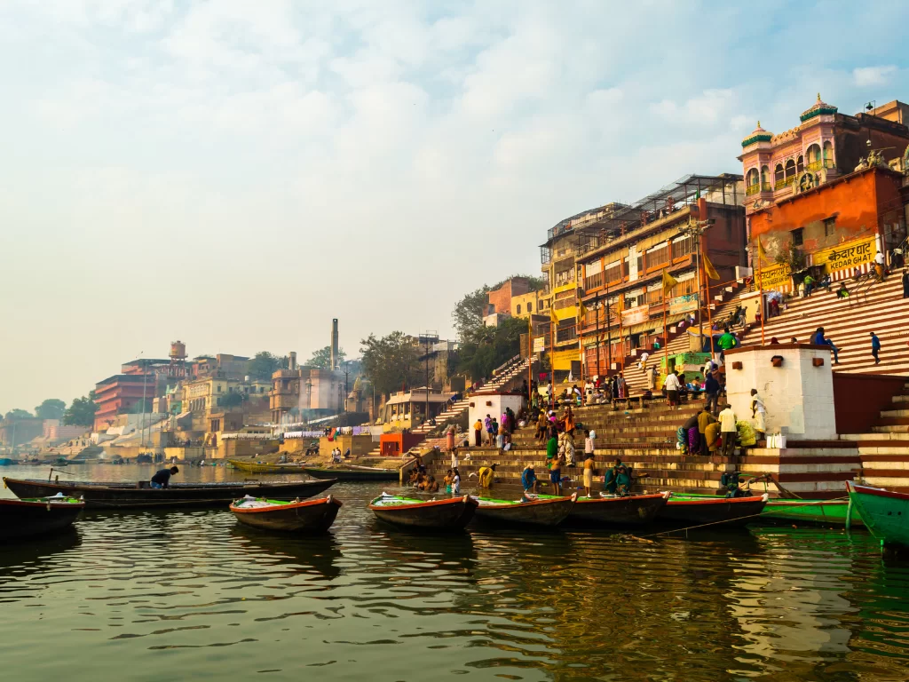 Kedar Ghat at Varanasi during sunrise, featuring colorful buildings boats steps reflections, perfect spiritual Uttar Pradesh tour package.