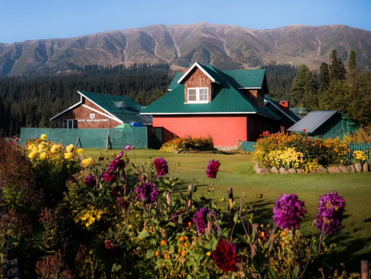 Resort with flower garden at Gulmarg during golden hour, featuring pine mountains backdrop, perfect romantic Srinagar tour package.
