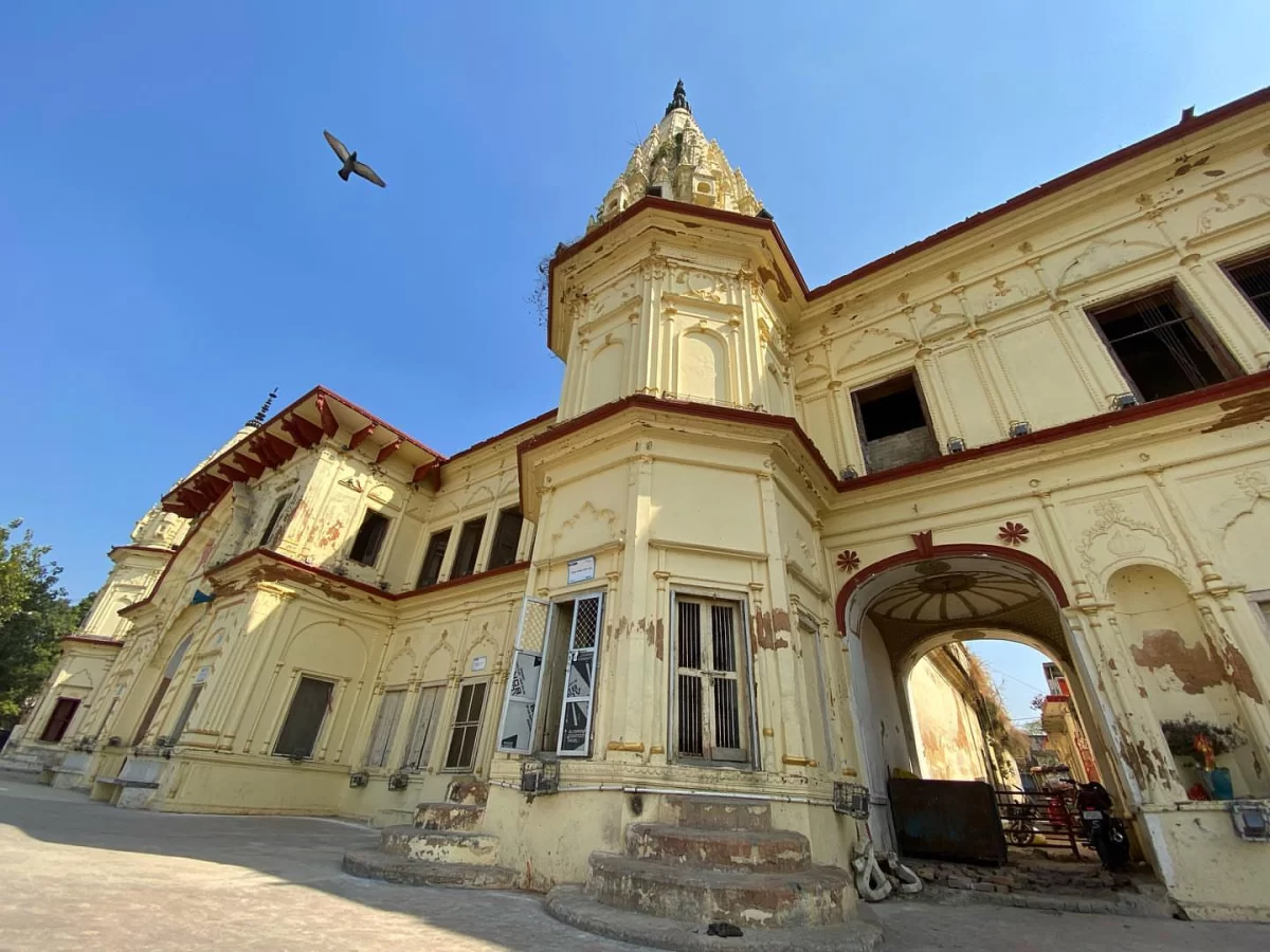 Historic palace at Guptar Ghat Ayodhya during clear day, featuring ornate shikhara and arched facade, perfect cultural experience Uttar Pradesh Tour Packages.