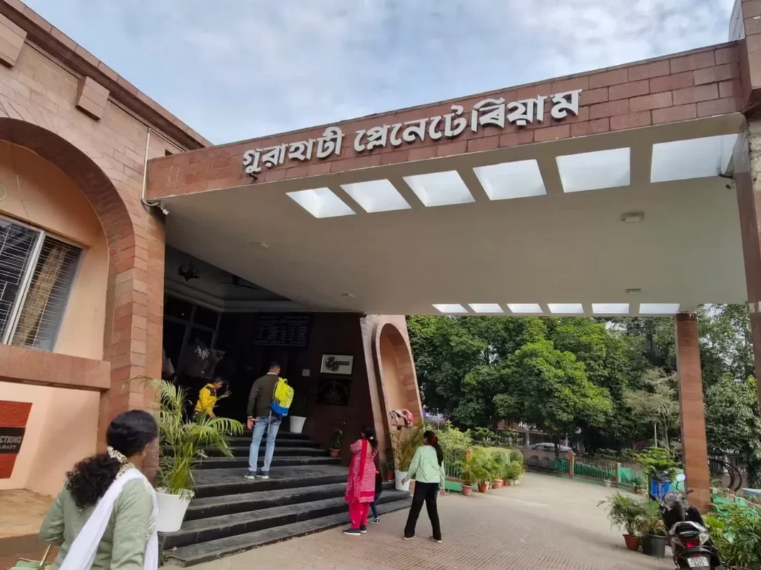 Visitors entering Guwahati Planetarium in Assam during daytime, featuring brick facade, glass canopy and garden path, perfect family experience Guwahati tour package.