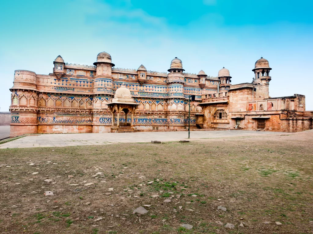 Man Mandir Palace at Gwalior Fort during clear afternoon, featuring turquoise tilework domes and intricate sandstone carvings, perfect heritage experience in Madhya Pradesh tour package.