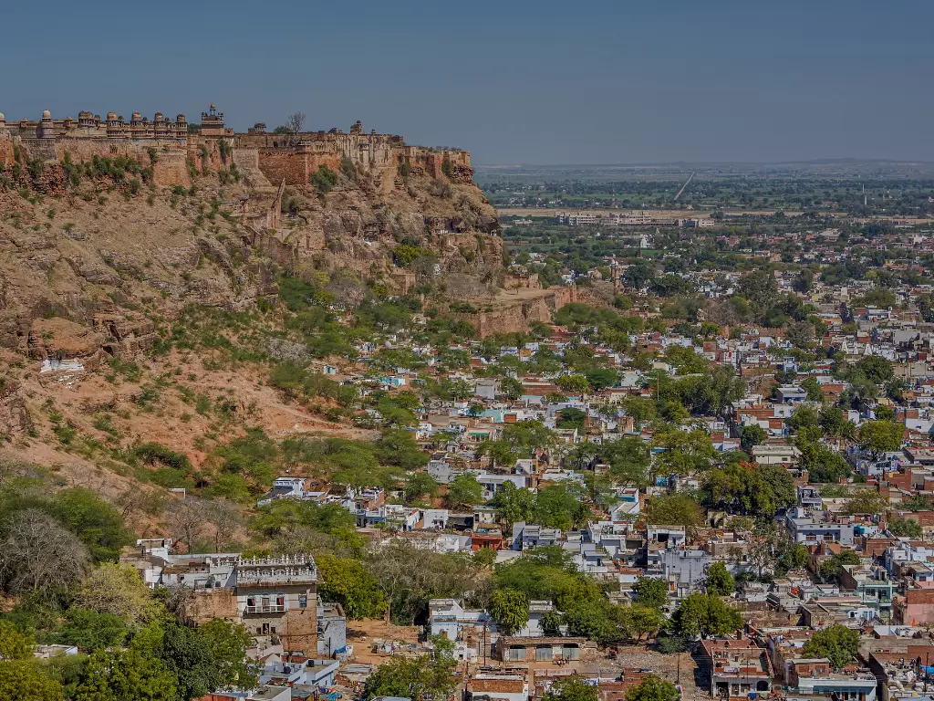 Gwalior Fort panoramic view during clear afternoon, showcasing hilltop ramparts overlooking sprawling cityscape, perfect heritage experience in Madhya Pradesh tour package.
