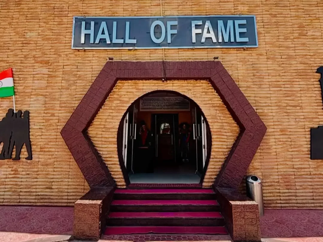 Hall of Fame museum Leh Ladakh Indian Army entrance building sign hexagonal maroon archway brick walls Indian flags silhouette soldiers purple carpet stairs military war memorial Kargil heroes.