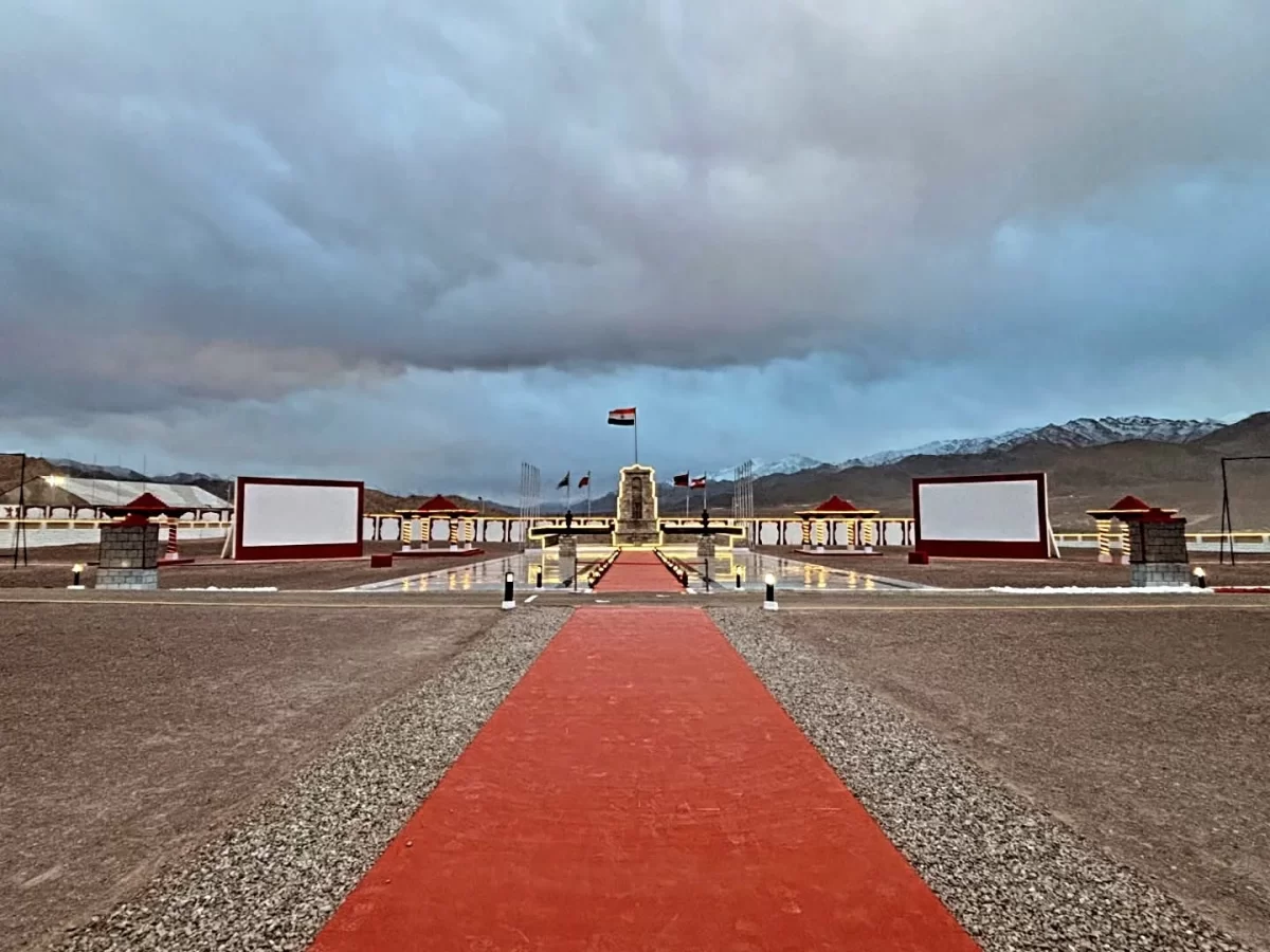 Hall of Fame Leh Ladakh Indian Army memorial cloudy evening red carpet pathway central cenotaph flagpole snowy mountains traditional Ladakhi red pagoda structures lit lamps military tribute.