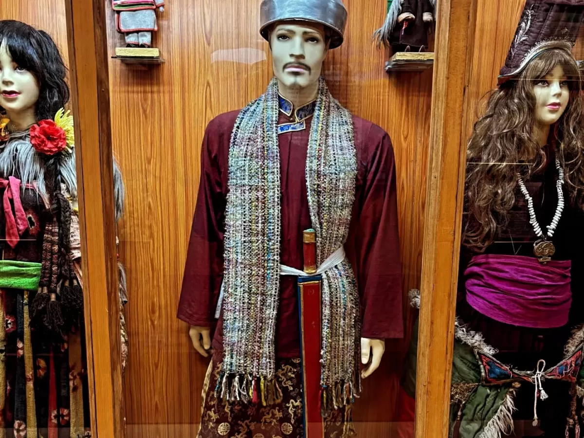 Hall of Fame Leh Ladakh Indian Army museum ethnographic display wooden case traditional Ladakhi Tibetan costumes mannequins maroon robe hat scarf sword woman dress fur hat flower necklace cultural heritage exhibit.