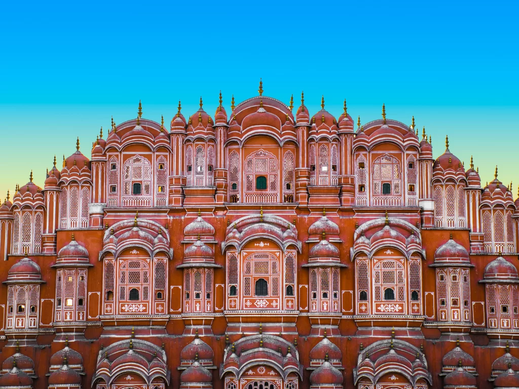 Hawa Mahal Jaipur vibrant blue sky, featuring pink honeycomb windows domes arches, perfect romantic experience Rajasthan tour packages.