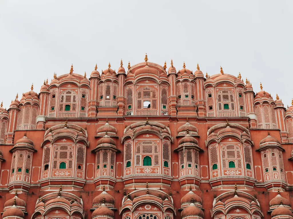 Hawa Mahal closeup Jaipur cloudy day, featuring pink jharokhas green shutters domes, perfect romantic experience Rajasthan tour packages.