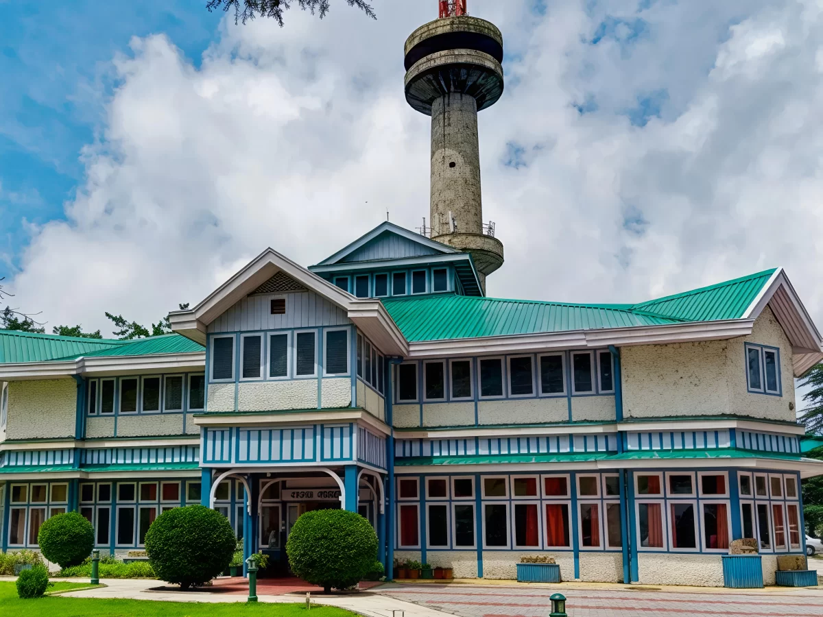 Himachal State Museum Shimla colonial green roofed building with prominent tower shrubs lawns partly cloudy sky, ideal history culture visit, Himachal Pradesh tour packages.