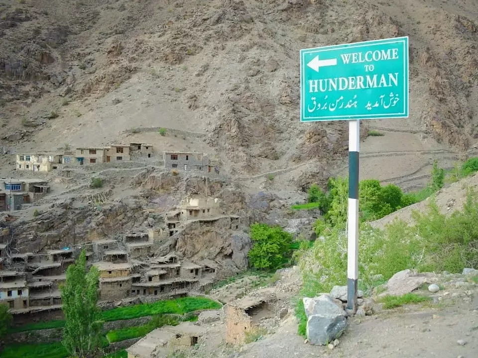 Welcome sign at Hunderman village during clear daytime, featuring mountain village houses, rocky cliffs, green valleys, perfect adventure experience with Ladakh tour package.