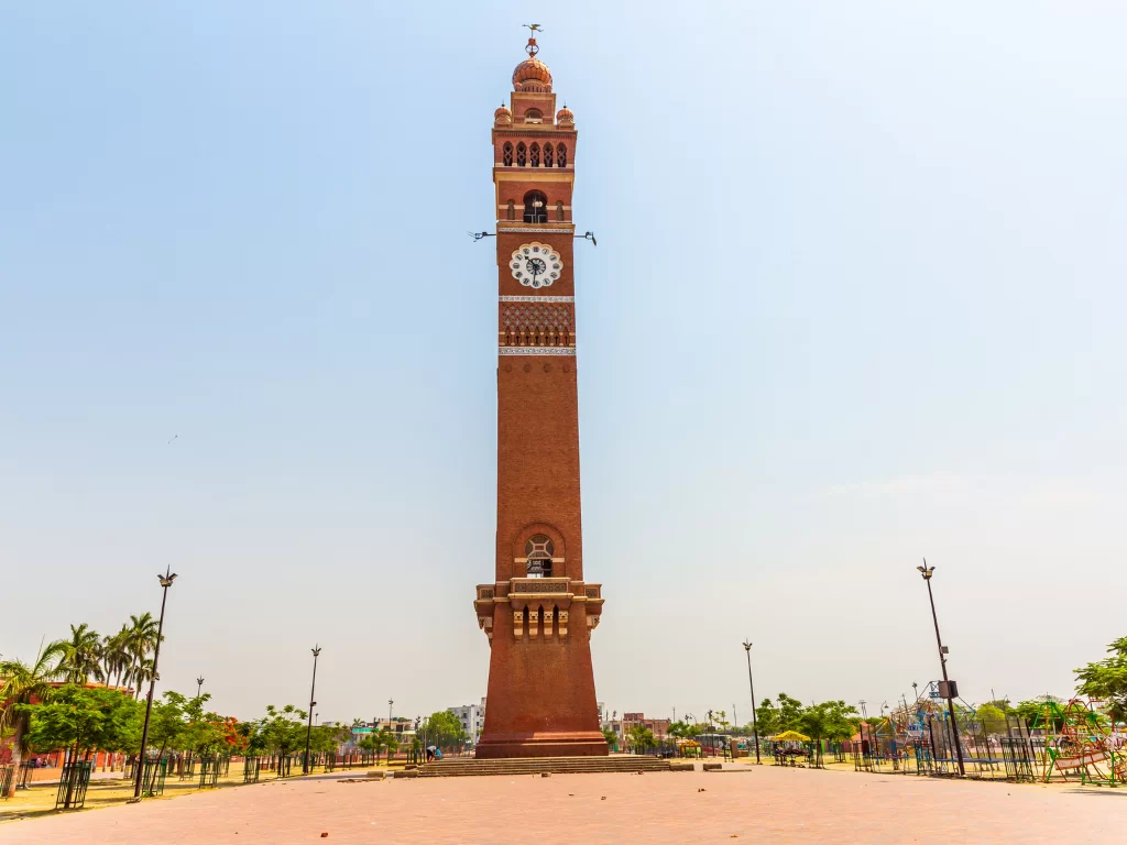 Hussainabad Clock Tower at Lucknow during daytime, featuring brick tower palms gardens plaza, perfect cultural Uttar Pradesh tour package.