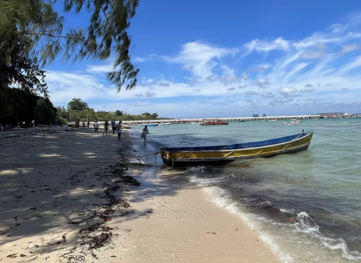 Bharatpur Beach Port Blair Andaman Nicobar golden-yellow hull traditional fishing boat beached on white sand, palm trees, turquoise waters, jetty with boats under partly cloudy blue skies, perfect eco beach Andaman tour package.