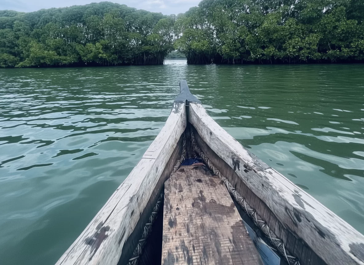 Traditional canoe ride in Mangrove Creeks at Baratang Island during cloudy daytime, featuring lush green canopy tunnel, emerald waters ahead, prop roots lining, perfect eco-adventure experience with Andaman tour package.