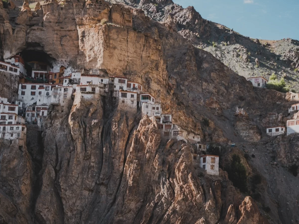 Phuktal Gompa Zanskar Ladakh white multi level cave monastery red roof buildings terraced rugged brown rocky cliff barren Himalayan mountain slope trees blue sky remote adventure trek pilgrimage tourism photography iconic vista.