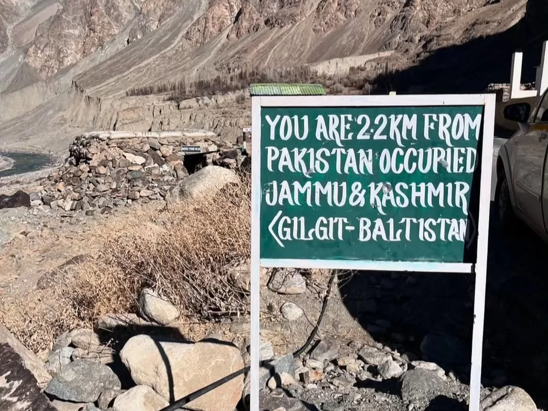 Turtuk village Ladakh Thang green sign You are 2 km from Pakistan occupied Jammu and Kashmir Gilgit Baltistan rocky hills car ruins, perfect northern border landmark tour package. 