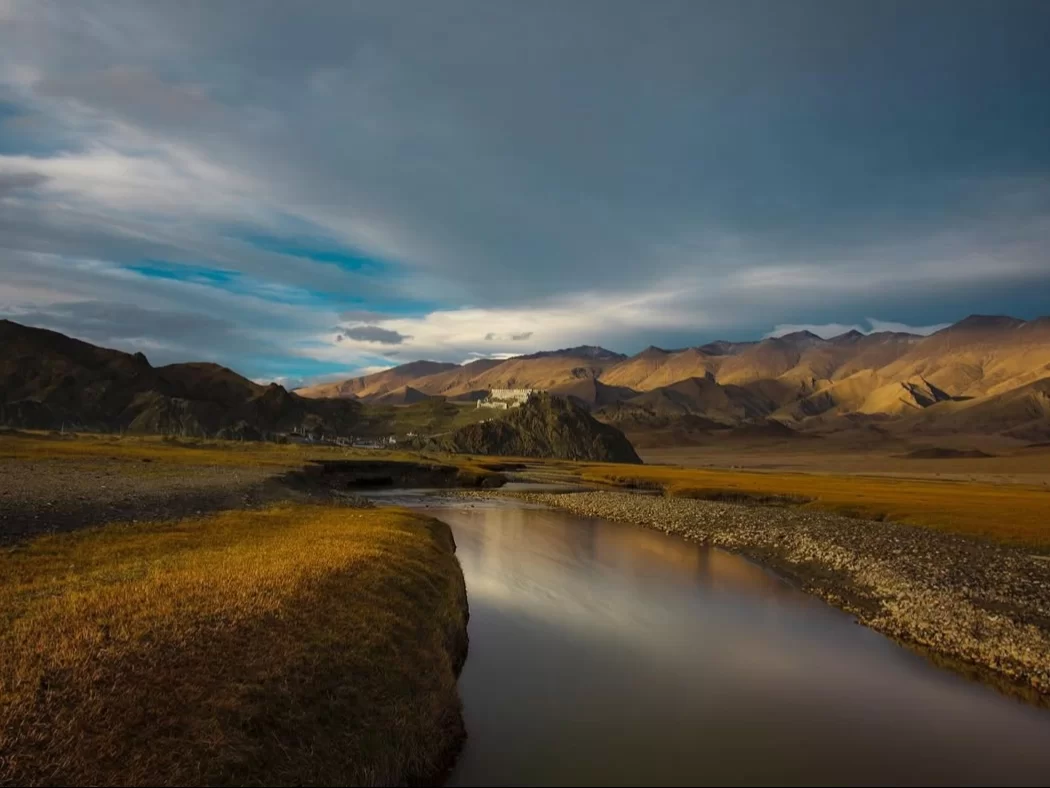 Hanle Ladakh landscape golden autumn grasslands reflective stream monastery rocky hills dramatic clouds sunset mountains, IIA observatory region high desert serenity, perfect Himalayan stargazing trekking package.