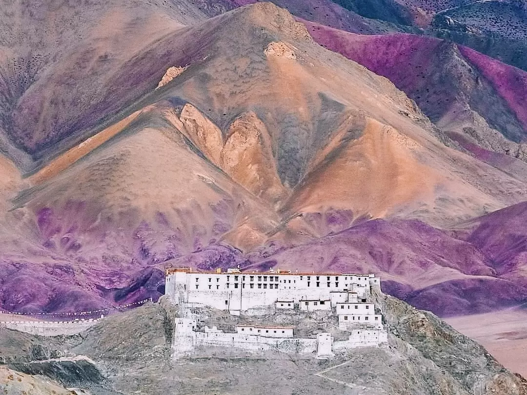 Hanle Monastery Ladakh vibrant purple orange terraced mountains white gompa fortress dramatic sunset colorful ridges Hanle Valley, Drukpa Kagyu spiritual gem observatory backdrop, perfect Himalayan serenity adventure package.