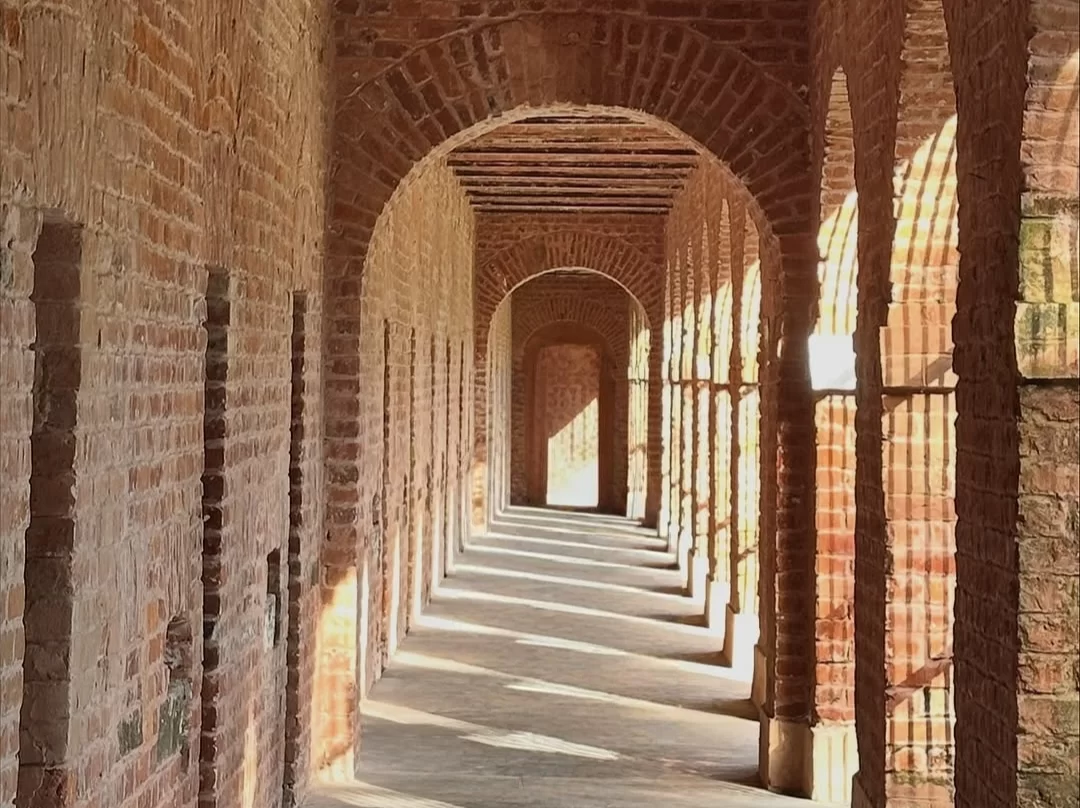 Cell arcade corridor at Cellular Jail Port Blair Andaman during golden hour, featuring brick arches, sunlight rays, cell niches, perfect heritage experience Andaman tour package.