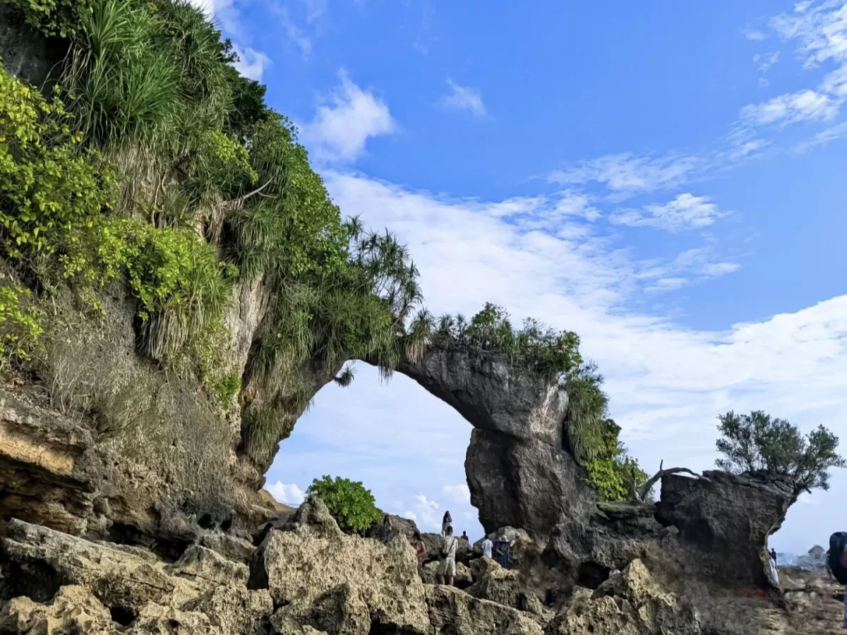 Natural limestone arch rock formation at Bharatpur Beach Neil Island Andaman Nicobar under clear blue skies with scattered clouds lush green vegetation and distant sea, iconic adventure Andaman tour package spot