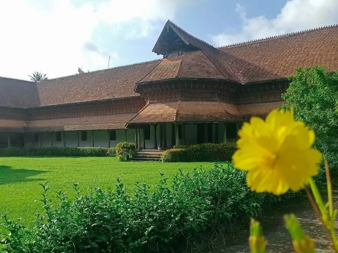 Kuthiramalika Palace Thiruvananthapuram Kerala traditional Kerala-style architecture with terracotta roofs, verandas and manicured green lawns under partly cloudy sky, perfect India tour package