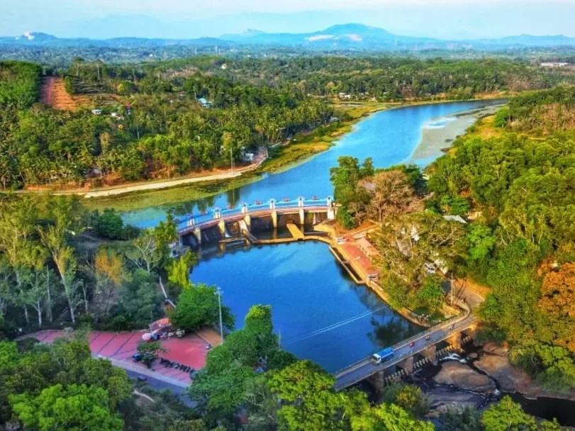 Aerial view of Aruvikkara Dam across Karamana River near Trivandrum during golden hour, featuring lush greenery, hills, perfect Kerala tour package.