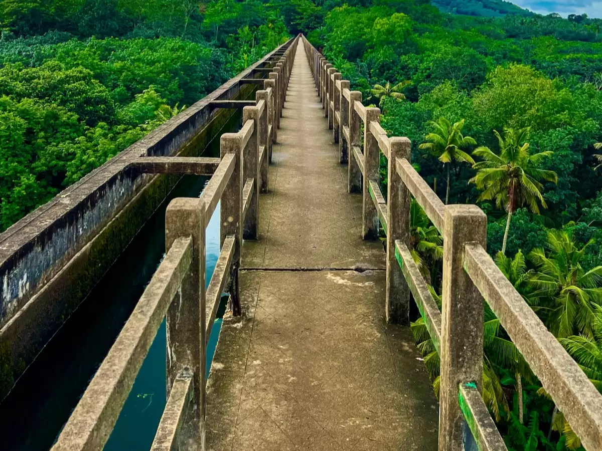 Mathoor Aqueduct Tamil Nadu eye-level trough channel view elevated concrete bridge railings flowing water lush forested hills coconut palms Kanyakumari longest aqueduct Pahrali irrigation marvel