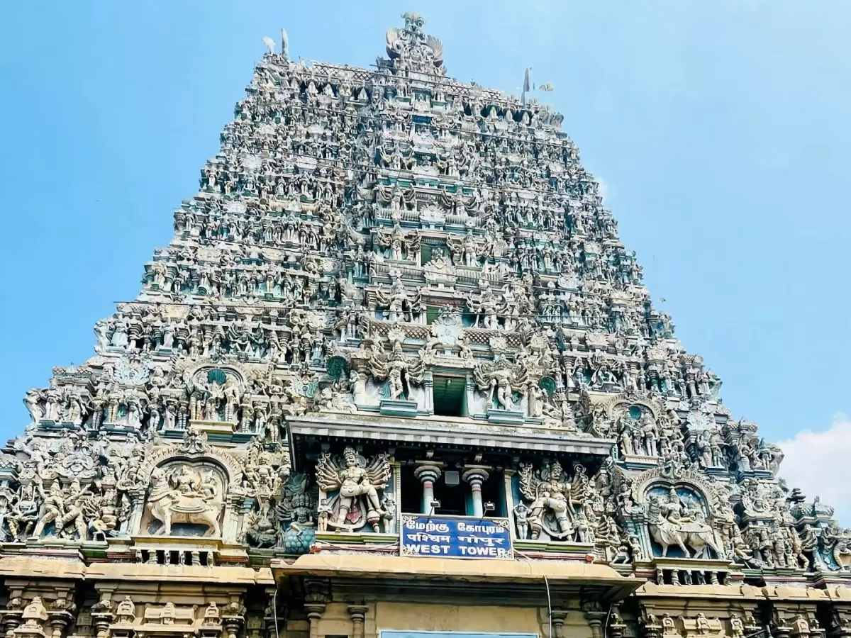 Meenakshi Amman Temple Madurai Tamil Nadu towering multi-tiered rainbow-hued gopuram entrance gate intricately carved with Hindu deities mythical figures blue sky backdrop Hindi Marathi signage, iconic Dravidian South Indian temple architecture heritage t