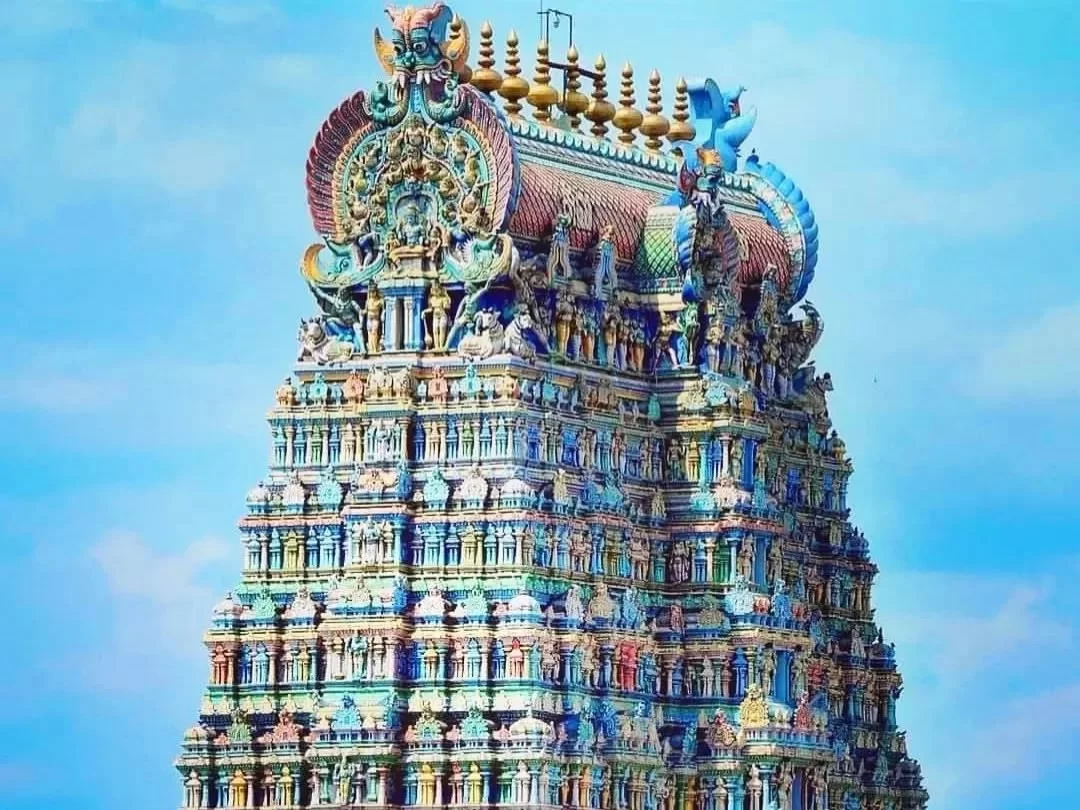Meenakshi Amman Temple Madurai Tamil Nadu stunning vertical view of ornate multi-tiered gopuram with golden vimana intricate rainbow deity carvings mythical birds under clear blue sky, legendary Dravidian Hindu temple tower architectural splendor heritage