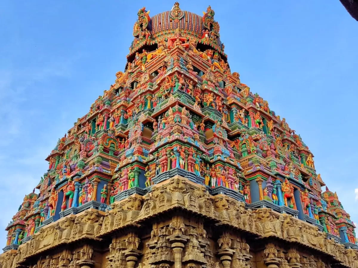 Upward perspective of vibrantly sculpted five-tiered Rajagopuram Arulmigu Koodal Azhagar Temple Madurai Tamil Nadu with intricate Dravidian stucco deities detailed stone base against clear blue sky, ideal for Madurai temple architecture photography