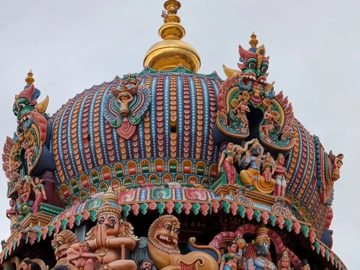 Close-up of Ashtanga Vimana top Arulmigu Koodal Azhagar Temple Madurai Tamil Nadu with multicolored stucco figures deities mythical creatures golden stupika striped roof lion motifs overcast sky, stunning Dravidian temple sculpture detail