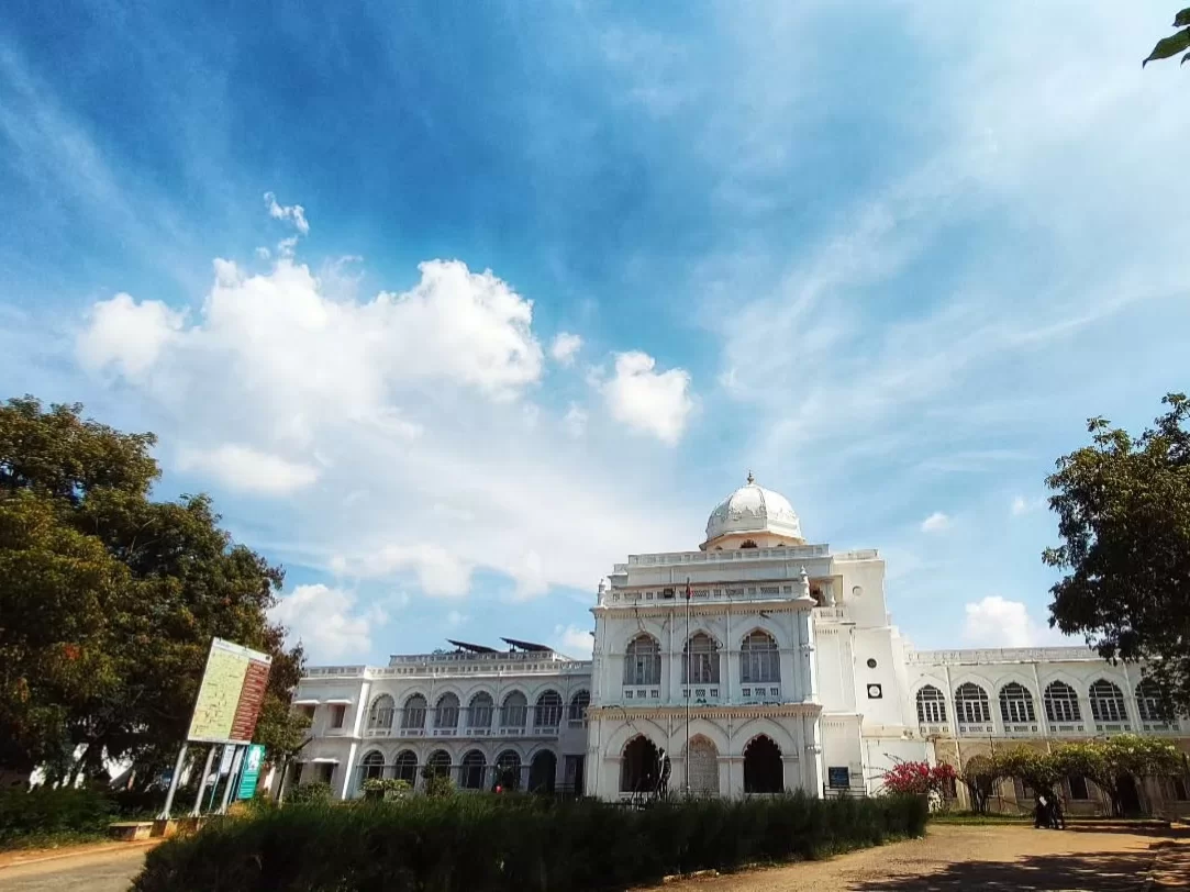 Gandhi Memorial Museum Madurai Tamil Nadu grand white colonial architecture with dome and arched windows surrounded by greenery under blue sky with scattered clouds, inspiring independence history tour package.